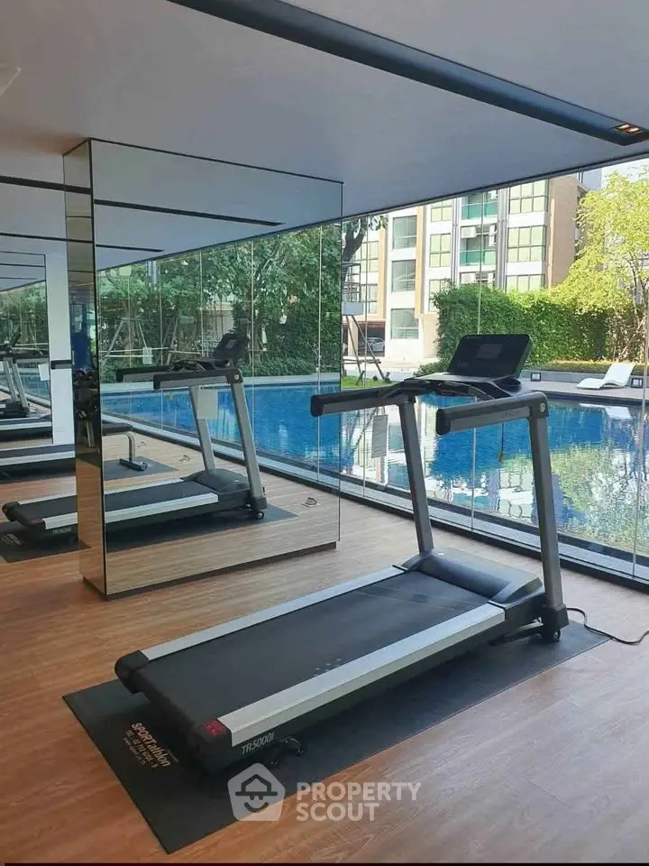 Modern gym with treadmill and pool view in luxury apartment complex