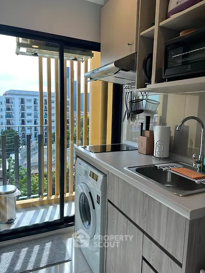 Modern kitchen with washing machine and balcony view in urban apartment
