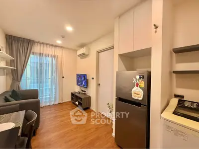 Modern living room with open kitchen, featuring sleek appliances and cozy seating area.