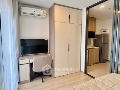 Modern bedroom with study area and kitchenette in a stylish apartment.