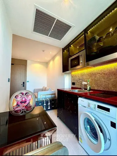 Modern kitchen with washing machine and microwave in compact apartment
