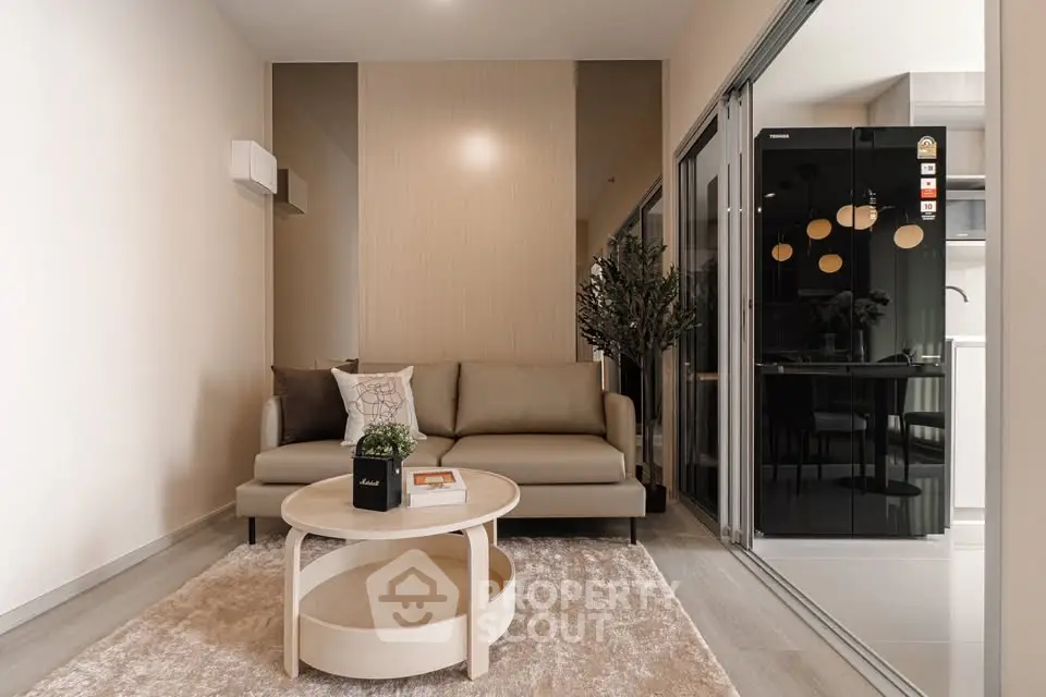 Modern living room with stylish sofa and round coffee table, adjacent to sleek kitchen area.