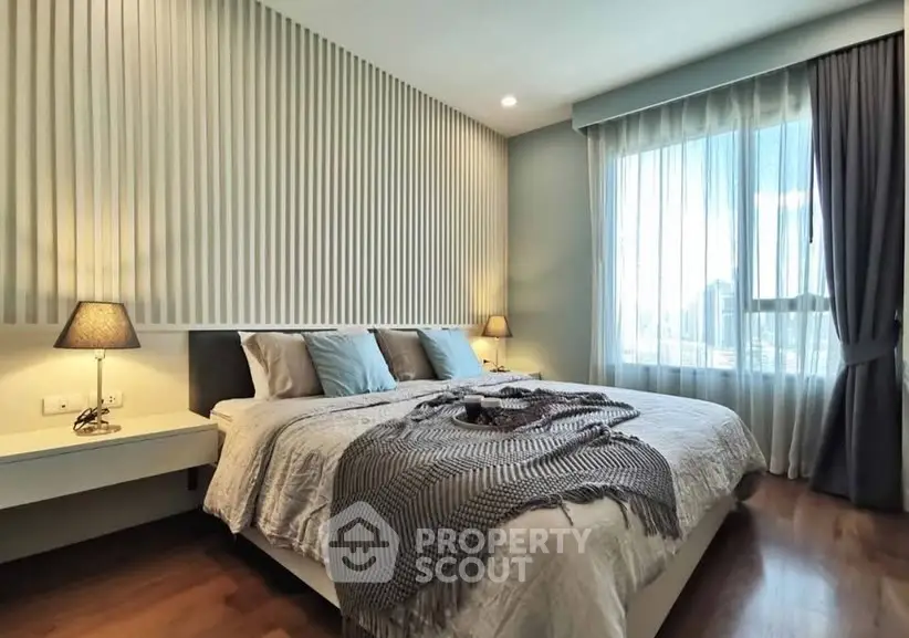 Elegant bedroom with modern decor and large window for natural light.