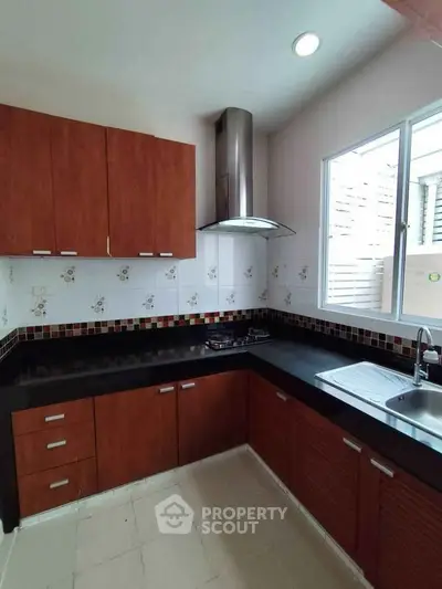 Modern kitchen with sleek cabinets and gas stove, featuring natural light and stylish backsplash.