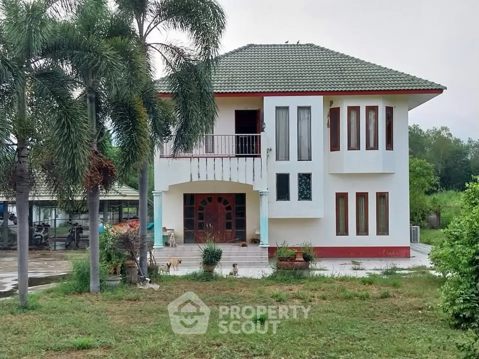 Charming two-story house with lush garden and palm trees, perfect for serene living.