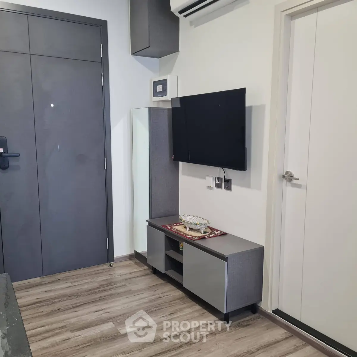 Modern living room with sleek furniture and wall-mounted TV, featuring stylish flooring and contemporary design.