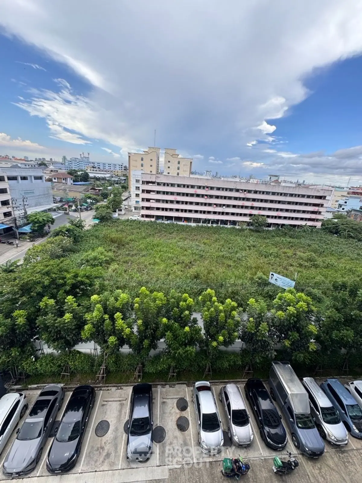 Scenic urban view with parking lot and lush greenery, perfect for real estate development.
