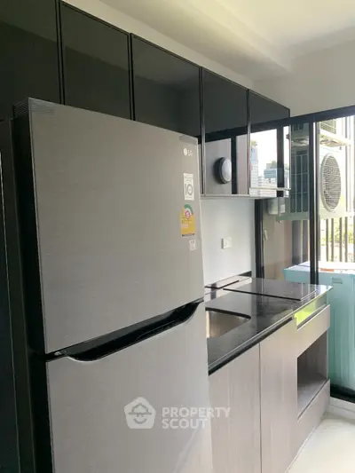 Modern kitchen with sleek cabinetry and stainless steel fridge in urban apartment