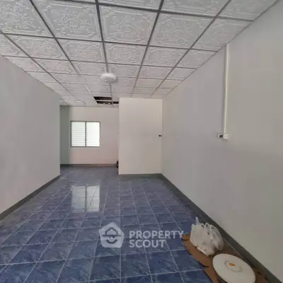 Spacious room with blue tiled floor and decorative ceiling tiles, ideal for customization.
