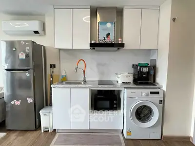 Modern kitchen with sleek white cabinets, washing machine, and stainless steel fridge.