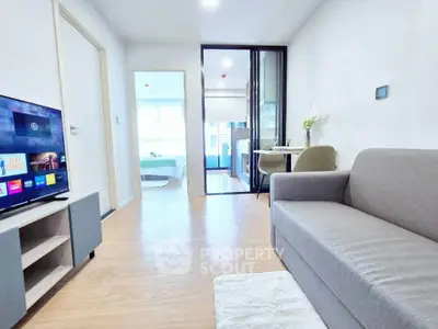 Modern living room with cozy sofa, TV, and dining area in open layout apartment.