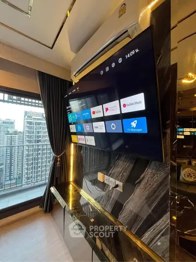 Luxurious living room with modern TV setup and stunning city view from large window.