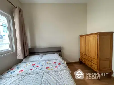 Cozy bedroom with wooden wardrobe and floral bedding in bright natural light