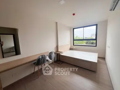 Modern bedroom with large window and minimalist furniture in a bright apartment.