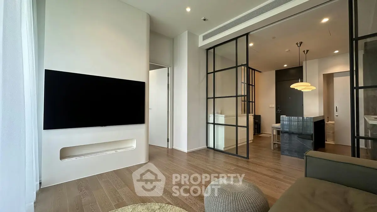 Modern living room with sleek design, featuring a wall-mounted TV and stylish glass partitions.