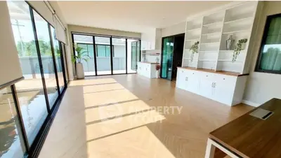 Spacious sunlit room with large windows and built-in shelves, ideal for modern living.