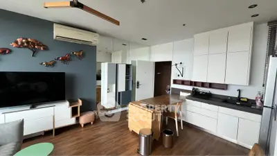 Modern living room with sleek kitchen, wooden flooring, and stylish decor in a contemporary apartment.