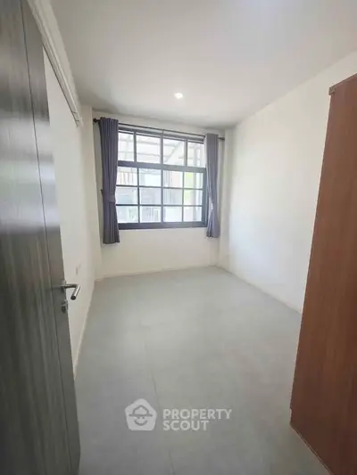 Spacious empty room with large window and natural light, perfect for customization.