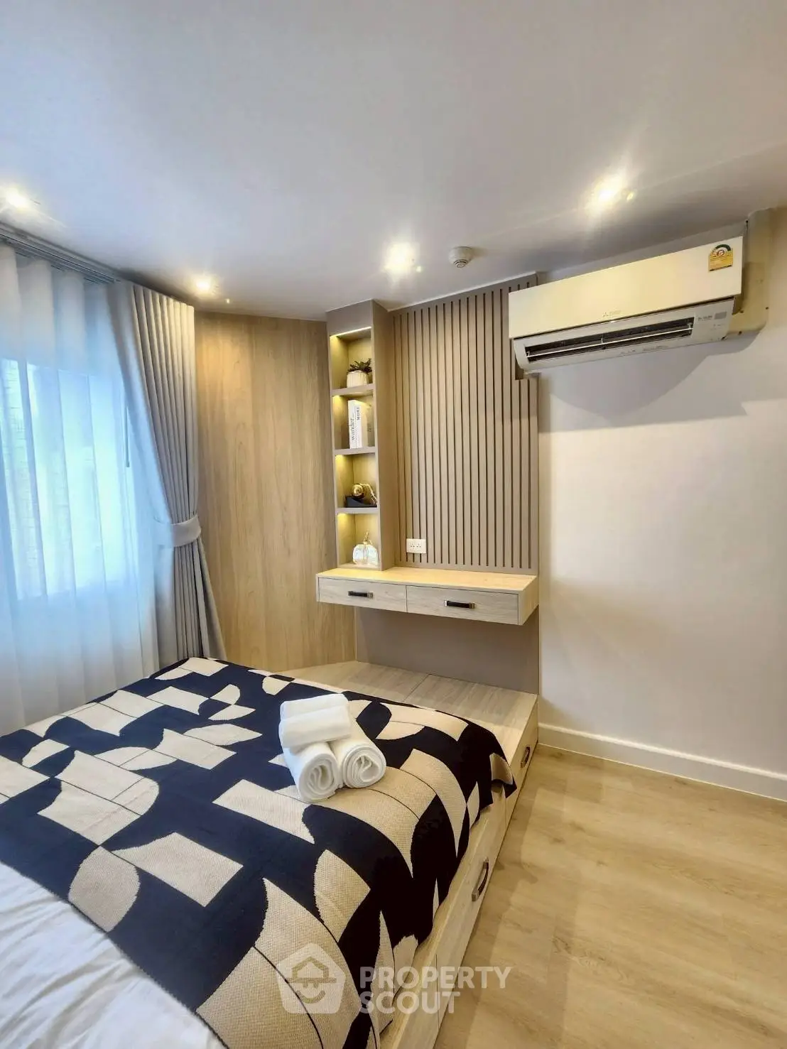 Modern bedroom with stylish decor and air conditioning, featuring cozy bed and elegant lighting.