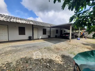 Charming rural property with spacious parking and rustic appeal under a clear blue sky.