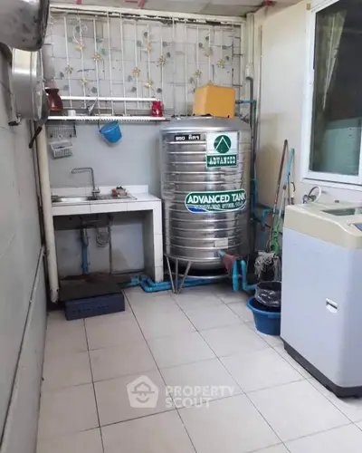 Utility area with water tank and washing machine in a tiled space