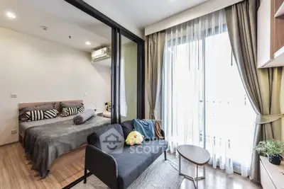Modern studio apartment with cozy living area and bedroom, featuring large windows and stylish decor.