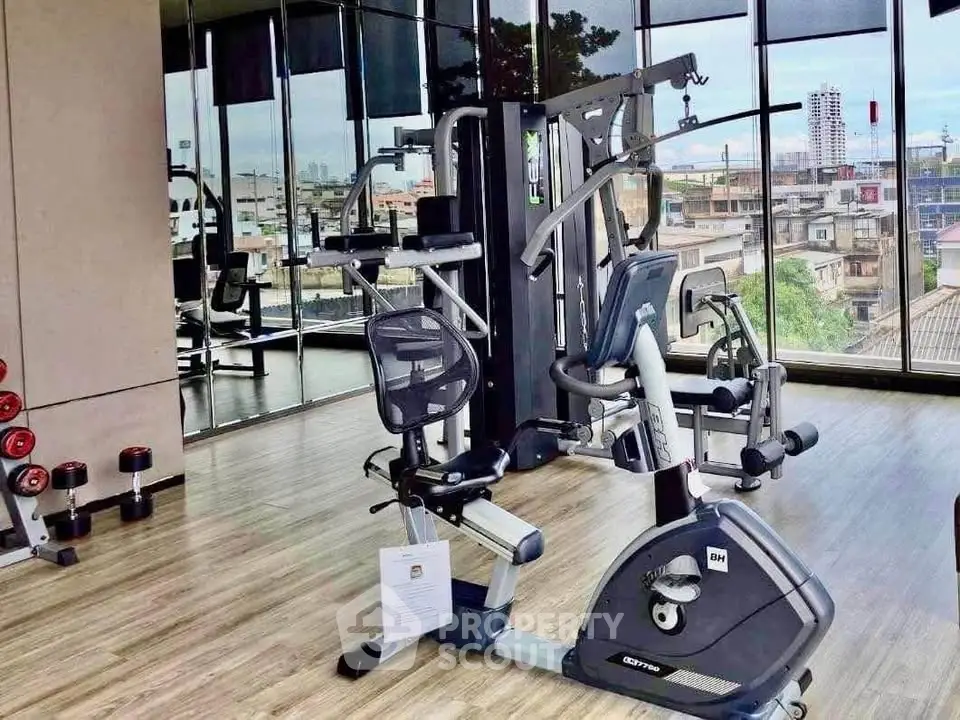 Modern gym with city view, featuring state-of-the-art exercise equipment and floor-to-ceiling windows.