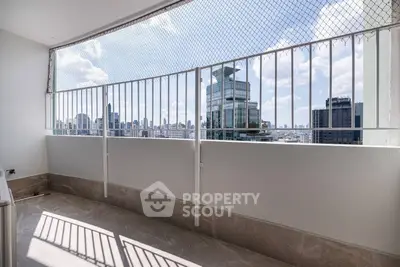 Spacious balcony with city skyline view and safety railing, perfect for relaxation.