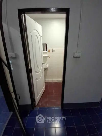 Compact bathroom with white door and tiled floor, ideal for small spaces.