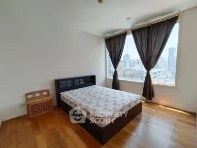 Spacious bedroom with city view and wooden flooring in modern apartment