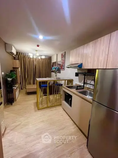 Modern kitchen with open layout and stainless steel appliances in cozy apartment.