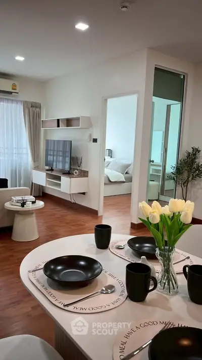 Modern living room with dining area and view into bedroom, featuring stylish decor and natural light.