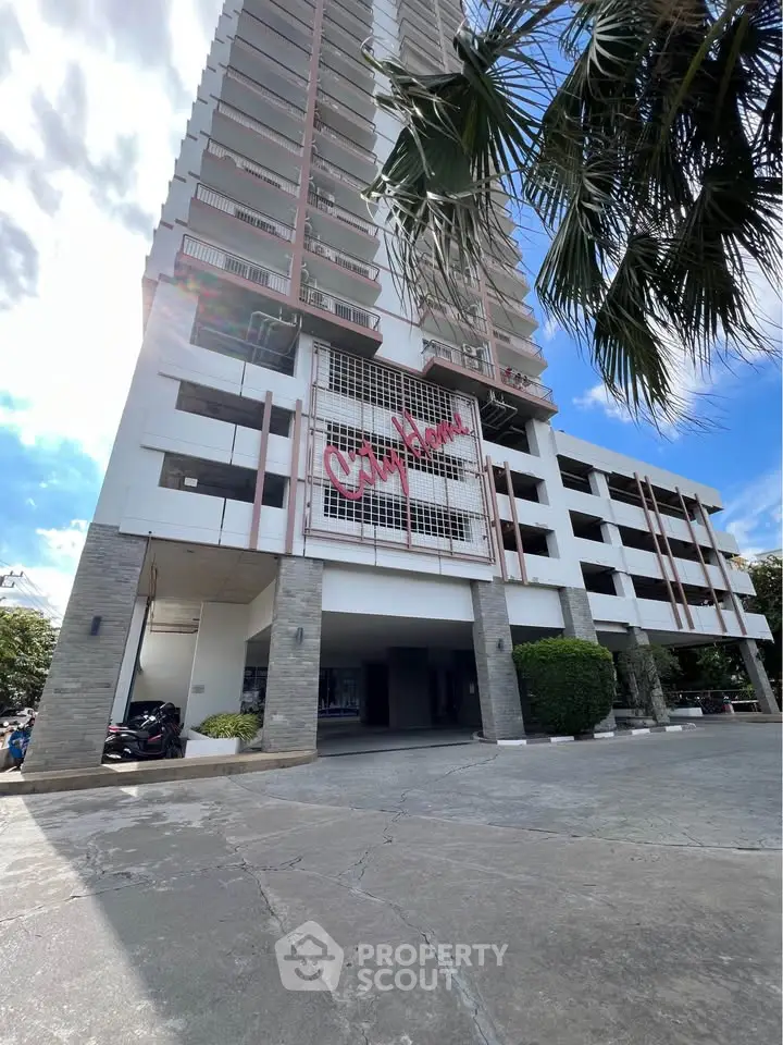 Modern high-rise building exterior with spacious entrance and palm trees, ideal for urban living.