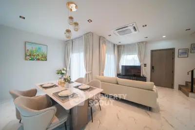 Elegant living room with modern decor, featuring a cozy sofa, dining area, and stylish lighting.