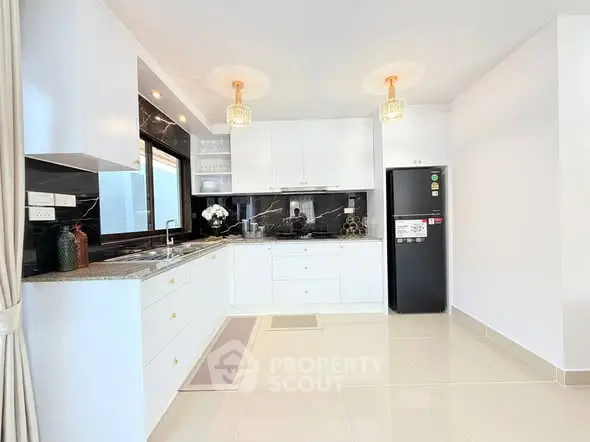 Modern kitchen with sleek white cabinets, black backsplash, and stainless steel appliances.