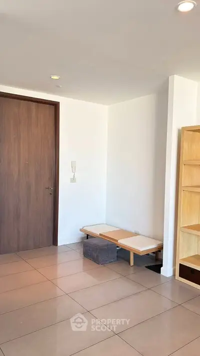 Modern minimalist entryway with wooden door and built-in shelving in a bright apartment.