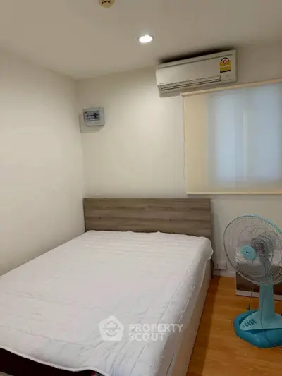 Cozy bedroom with air conditioning and fan, featuring a comfortable bed and minimalist decor.