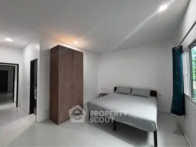 Spacious bedroom with modern design and ample natural light, featuring a large wardrobe and minimalist decor.
