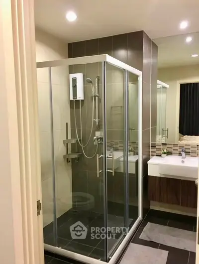 Modern bathroom with glass shower enclosure and sleek vanity in contemporary apartment.