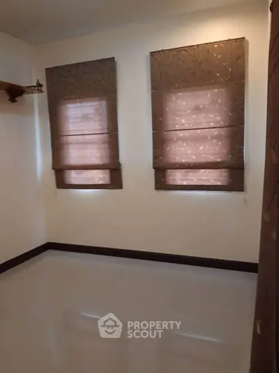 Spacious empty room with elegant brown blinds and glossy flooring, perfect for customization.