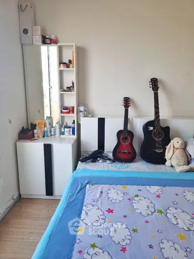 Cozy bedroom with guitars and plush toy, perfect for music lovers.