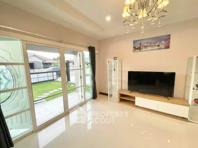 Spacious living room with modern decor and large glass doors opening to a garden view.
