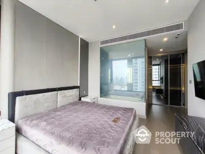 Luxurious modern bedroom with city view and glass-walled ensuite bathroom