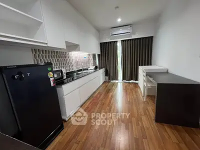 Modern kitchen with sleek cabinetry and hardwood floors in a contemporary apartment.