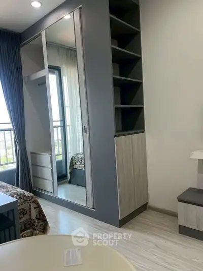 Modern bedroom with built-in wardrobe and balcony view, featuring sleek design and ample natural light.