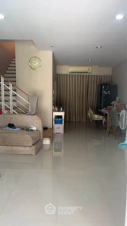 Spacious living room with modern decor and open layout, featuring a staircase and dining area.