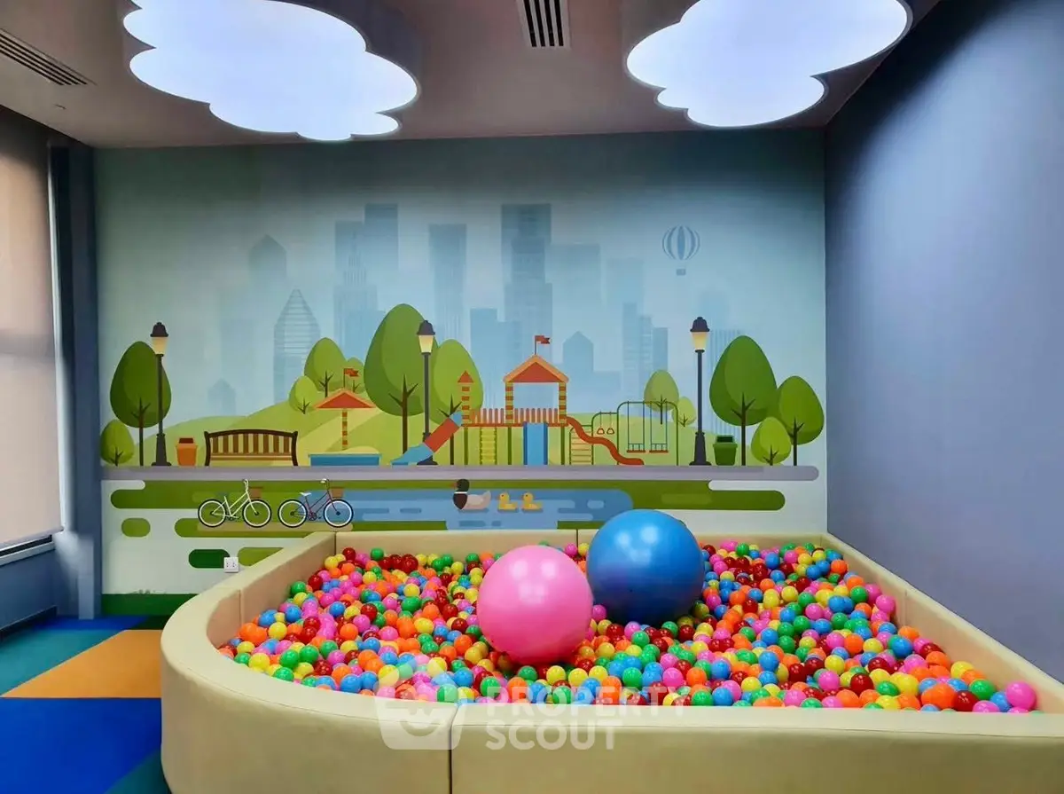 Vibrant indoor play area with colorful ball pit and playful wall mural in modern building.