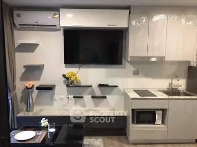Modern living room with sleek kitchen, wall-mounted TV, and stylish shelving in a contemporary apartment.