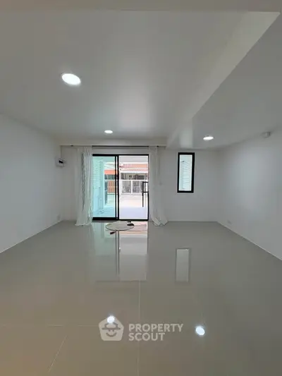 Spacious modern living room with large windows and glossy tiled floor, perfect for natural light lovers.