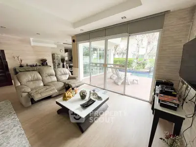 Spacious living room with modern decor and poolside view, perfect for relaxation and entertainment.